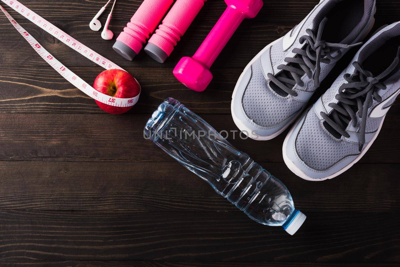 Pair sports shoes, headphones, dumbbell and water bottle on black wood table background, Gray sneakers and accessories equipment in fitness GYM, Healthy workout active lifestyle diet concept