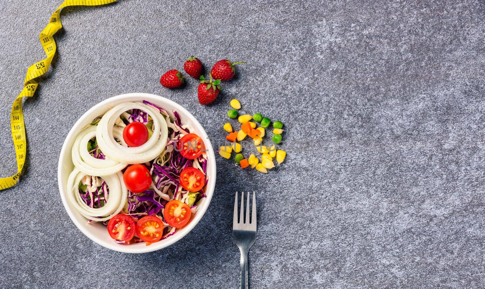 Top view of the healthy colorful salad bowl with tomatoes fresh mixed greens vegetable in a dish and measuring tape on cement background, Health salad snack diet food weight loss concept