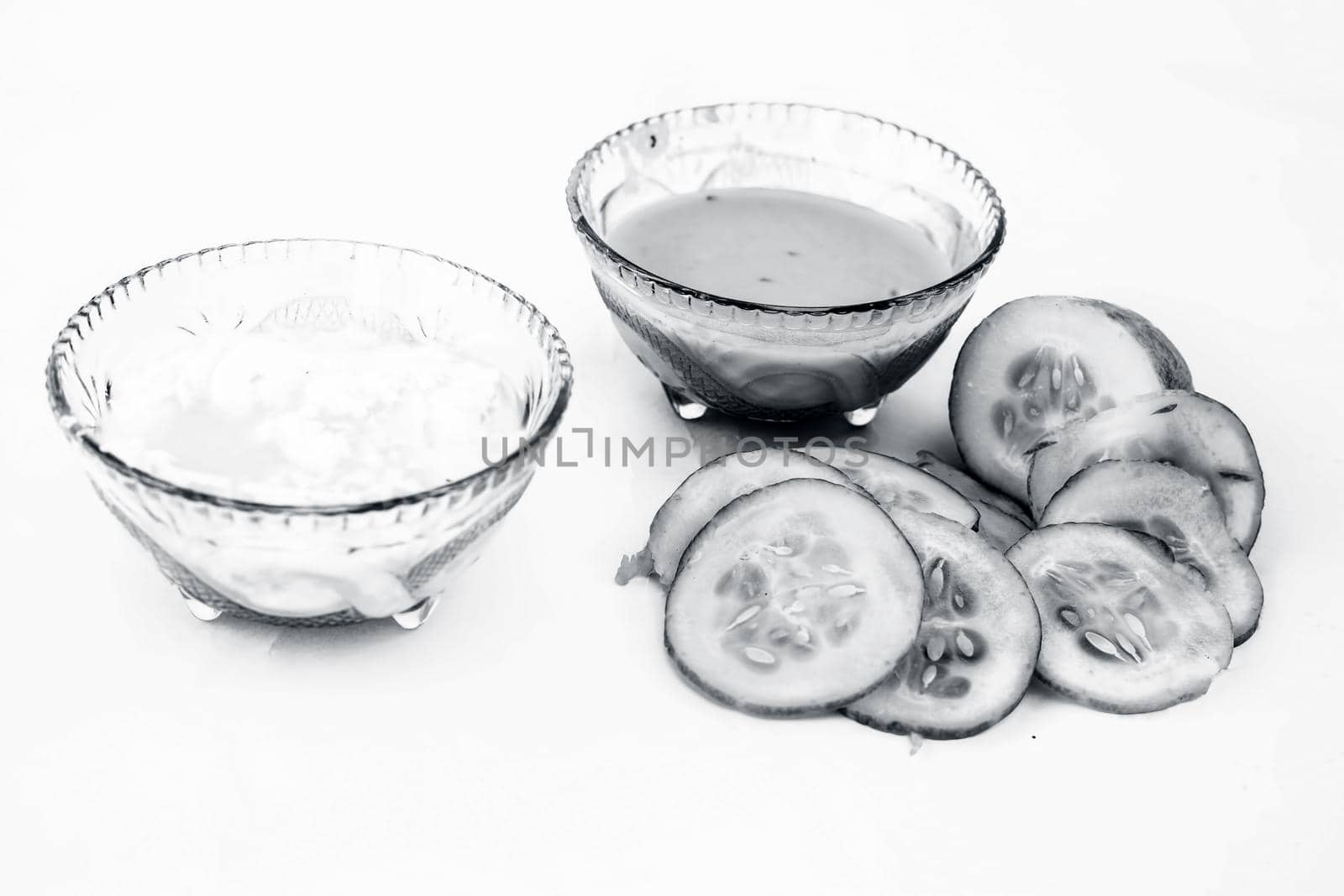 Cucumber face pack isolated on white i.e. Cucumber pulp well mixed with dahi or yogurt in a glass bowl and entire raw ingredients present on the surface.Used to cure acne prone skin.