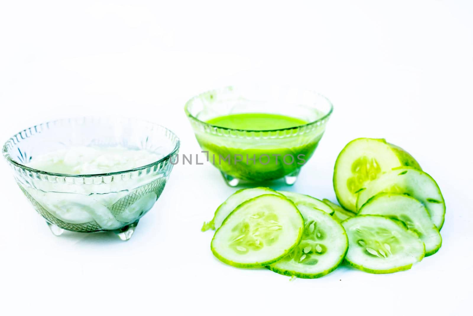 Cucumber face pack isolated on white i.e. Cucumber pulp well mixed with dahi or yogurt in a glass bowl and entire raw ingredients present on the surface.Used to cure acne prone skin.