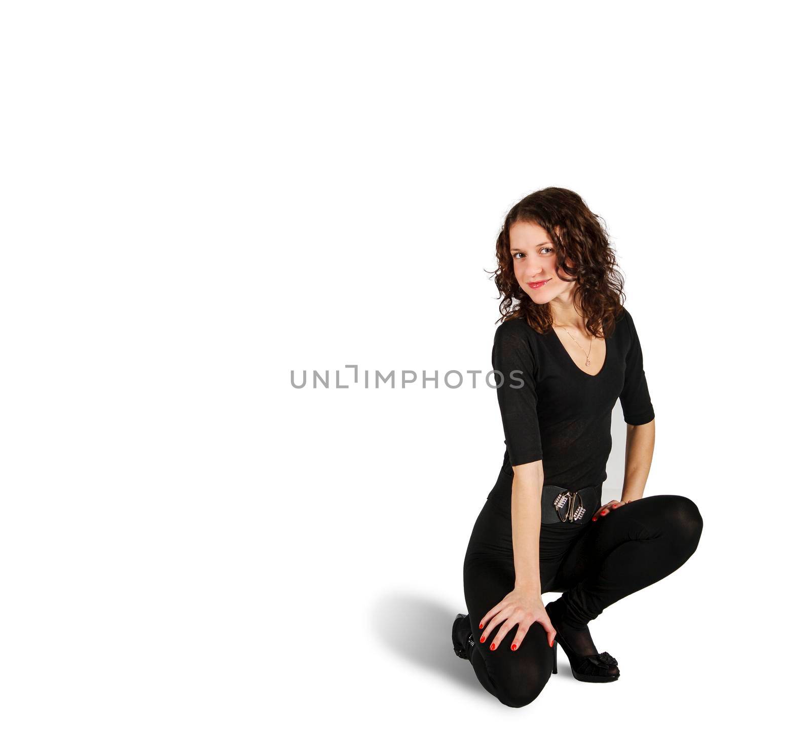 young beautiful woman in black suit posing crouching in studio on white background