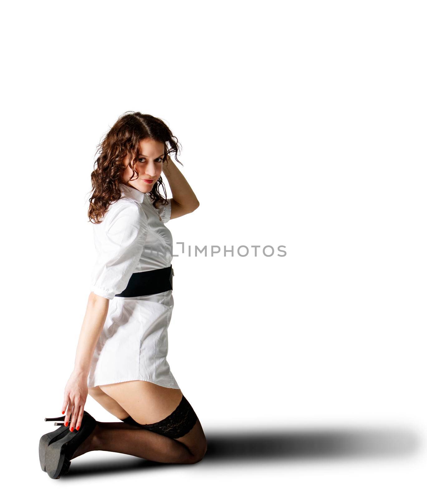 young beautiful woman in white short dress posing in studio kneeling on white background
