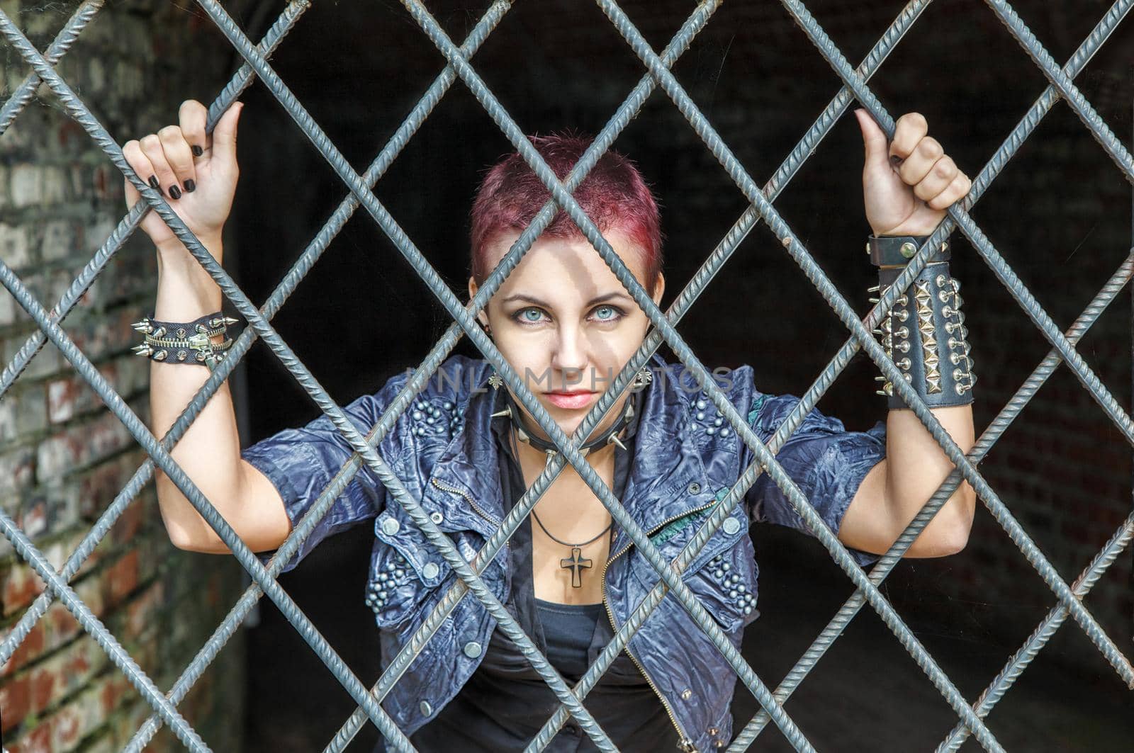 young pretty punk girl standing behind bars
