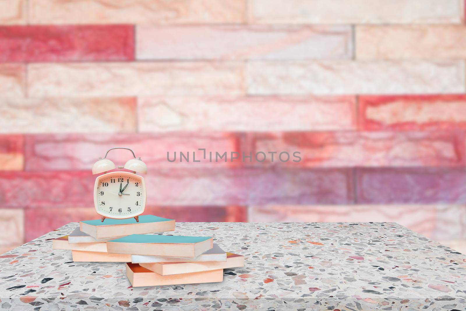 alarm clock and books on stone shelf in library school concept with brick wall blur background copy space add text by pramot