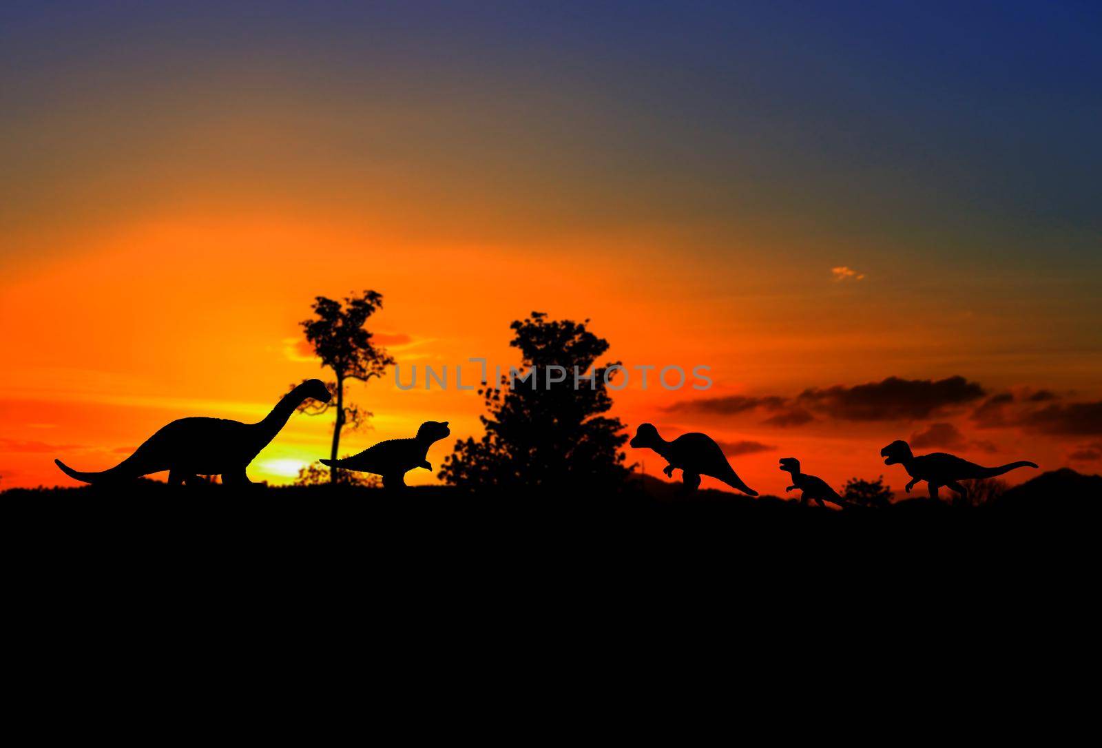 silhouettes of dinosaurs in the forest on sunset background with copy space add text by pramot