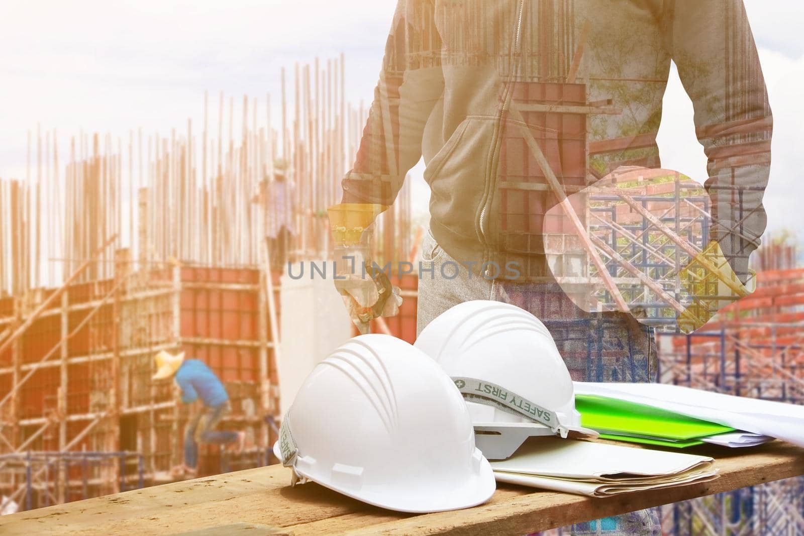 white safety helmet and paper plan blueprint on wood floor table with concept Double Exposure engineering in working building construction site background