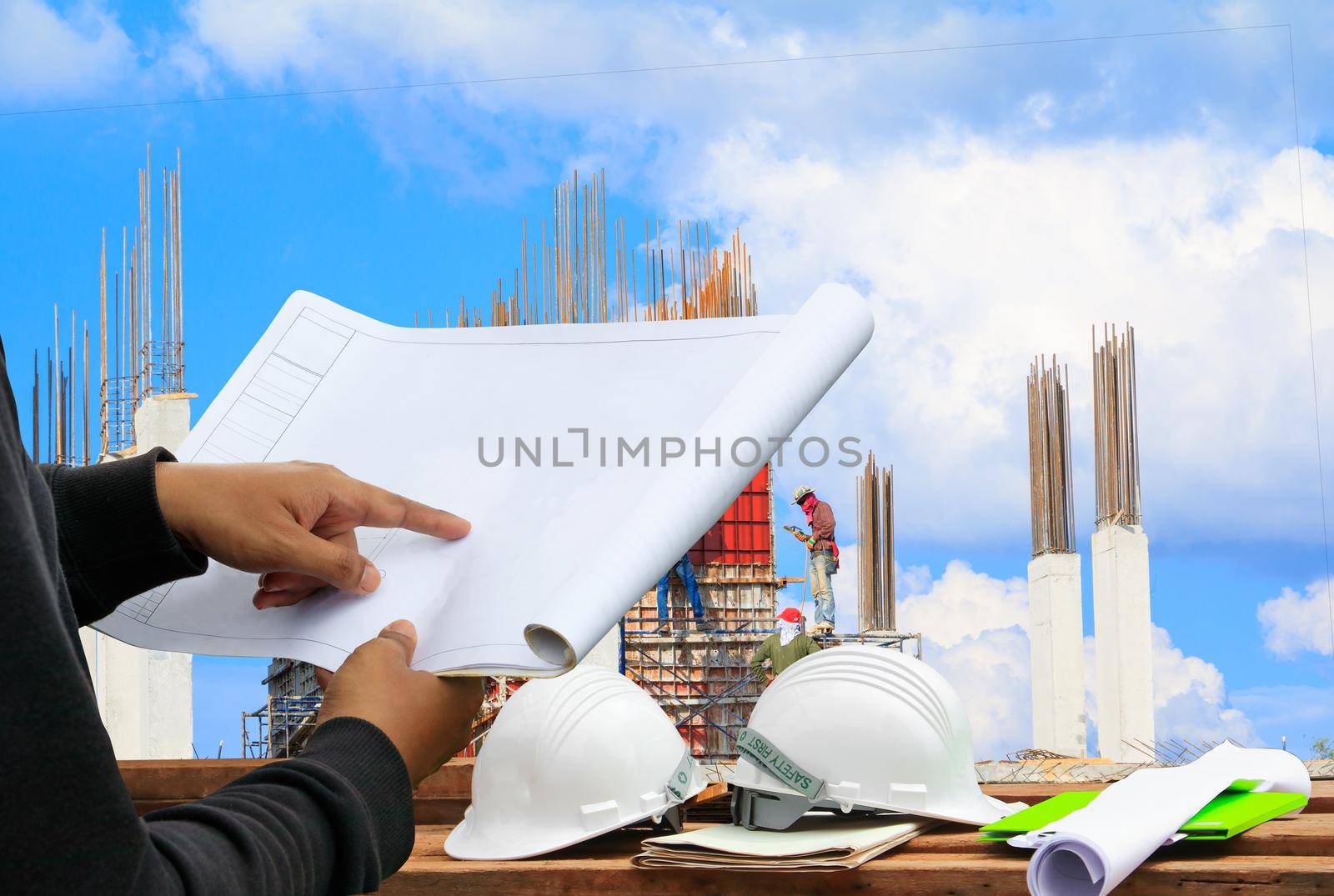 engineer finger point on paper plan blueprint in check building technician place construction site and two white safety helmet on wood floor table with copy space add text by pramot