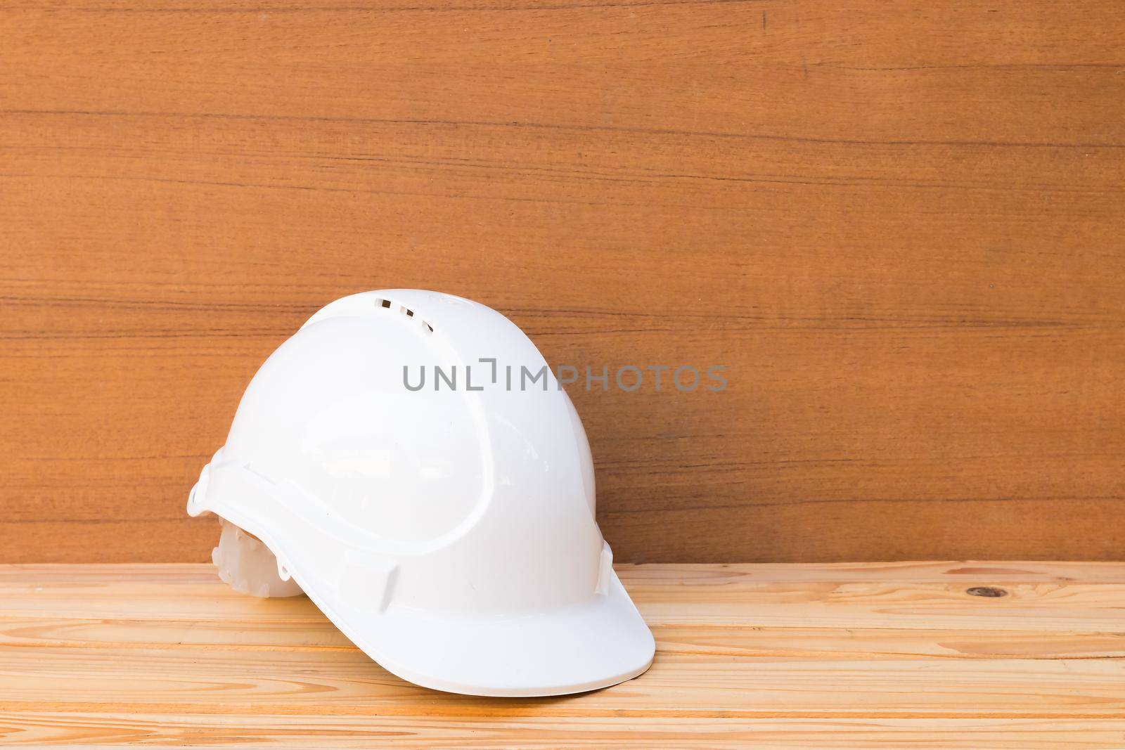 white safety helmet plastic construction of engineering on wood floor table background with copy space add text