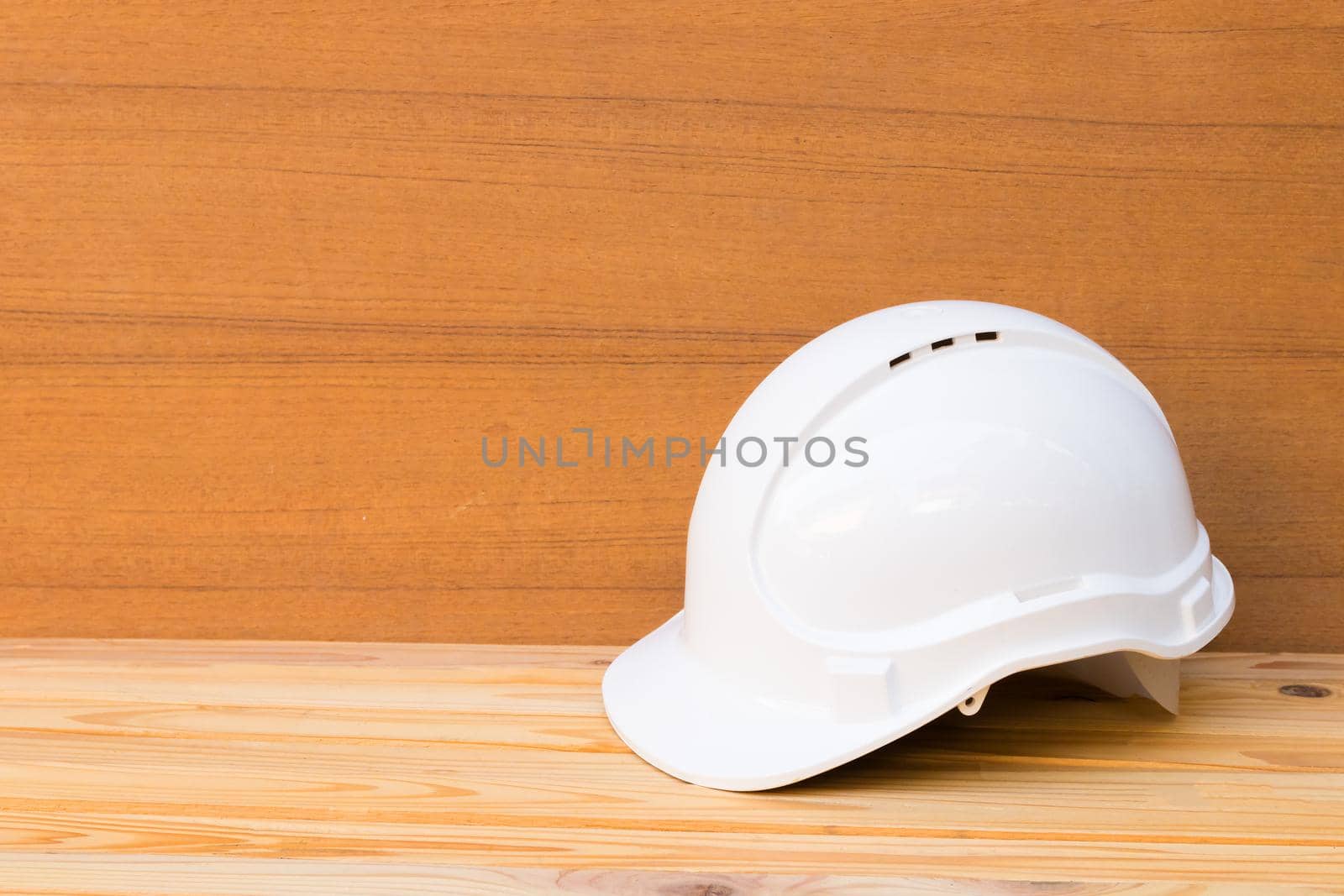 white safety helmet plastic construction of engineering on wood floor table background with copy space add text by pramot