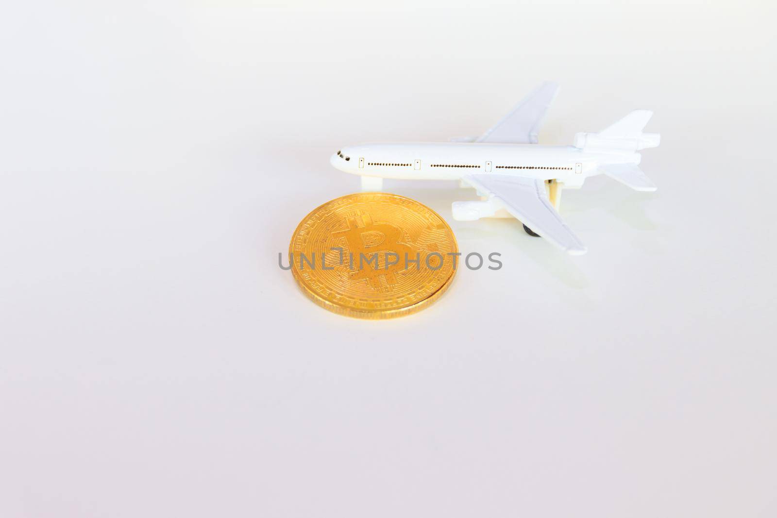 bitcoin coins and model of passenger plane  over white on black background. with copy space add text