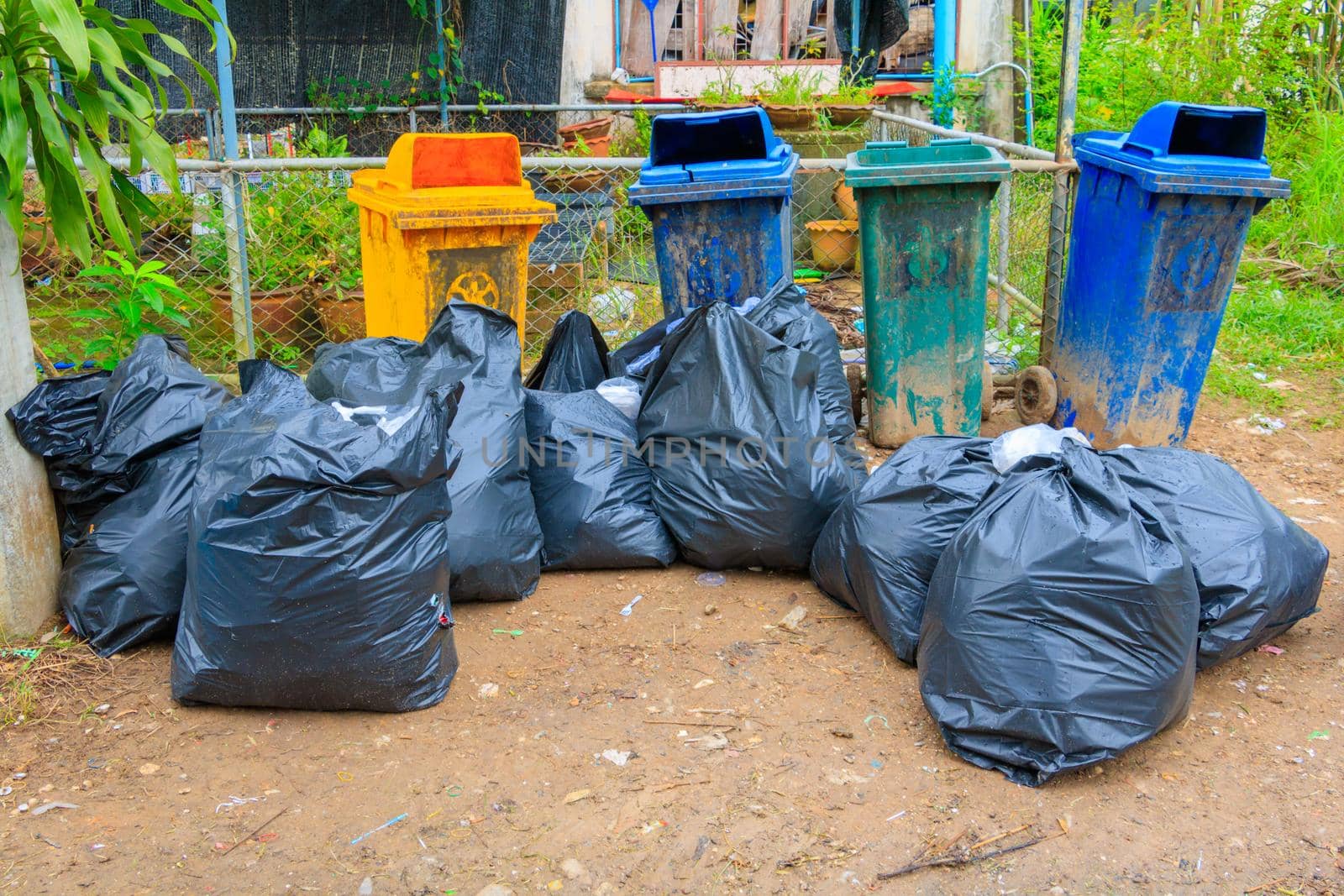 pile black garbage bag plastic and four dustbin dirty roadside in the city by pramot