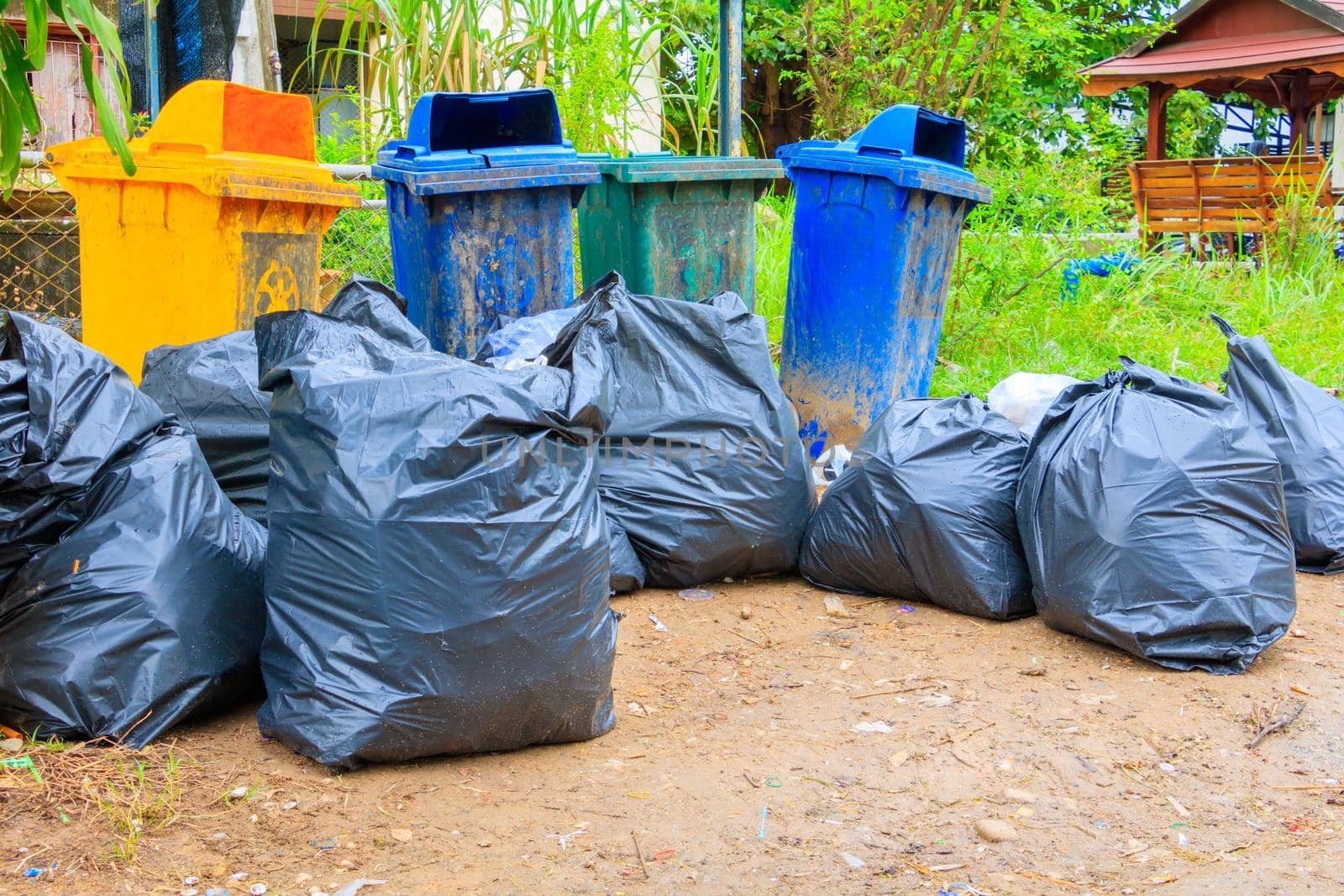 pile black garbage bag plastic and four dustbin dirty roadside in the city by pramot