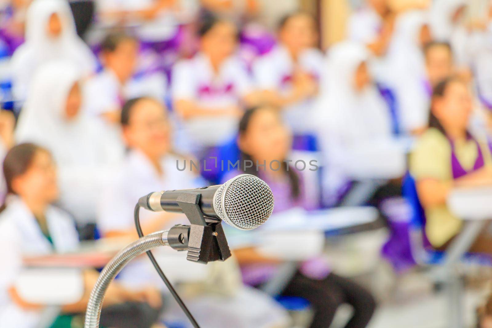 Close up microphone stand on the table in the conference and Background blur interior seminar meeting room. select focus with shallow depth of field. by pramot