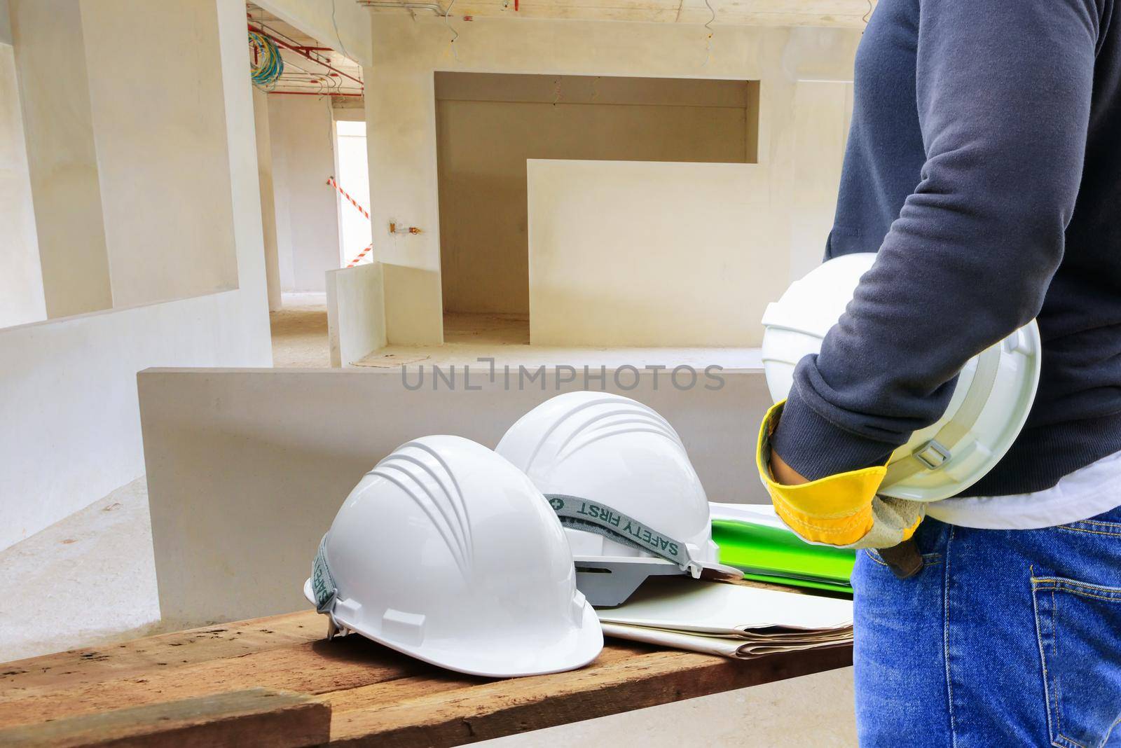 engineering hand holding white safety hat interior working construction site in building  with copy space add text by pramot