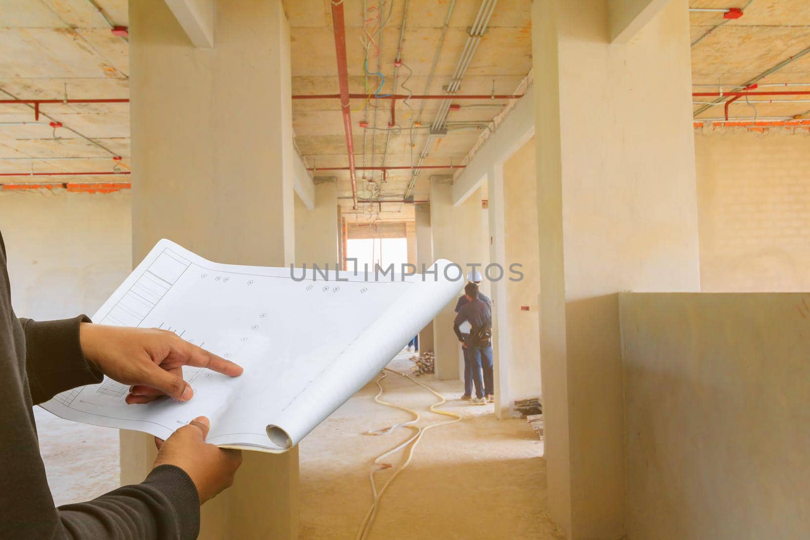 engineer finger point on paper plan blueprint in check building technician place construction site wall interior with copy space add text