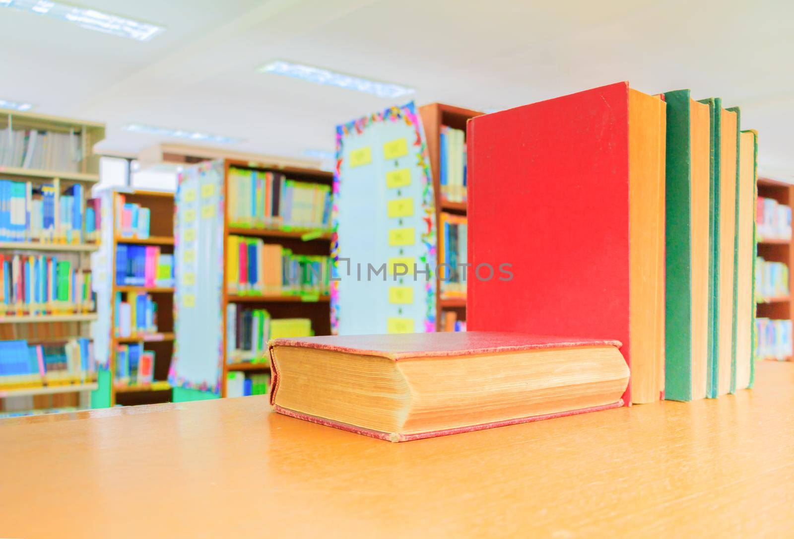 old book red - green. heap are interior library school on wooden table and blurry bookshelves background. education learning concept with copy space add text by pramot