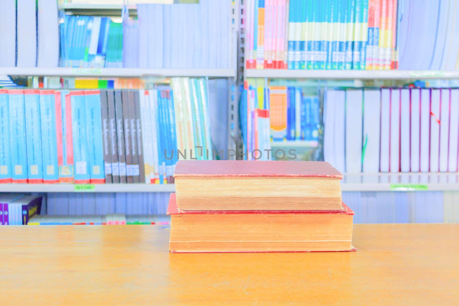 old book red - green. heap are interior library school on wooden table and blurry bookshelves background. education learning concept with copy space add text by pramot