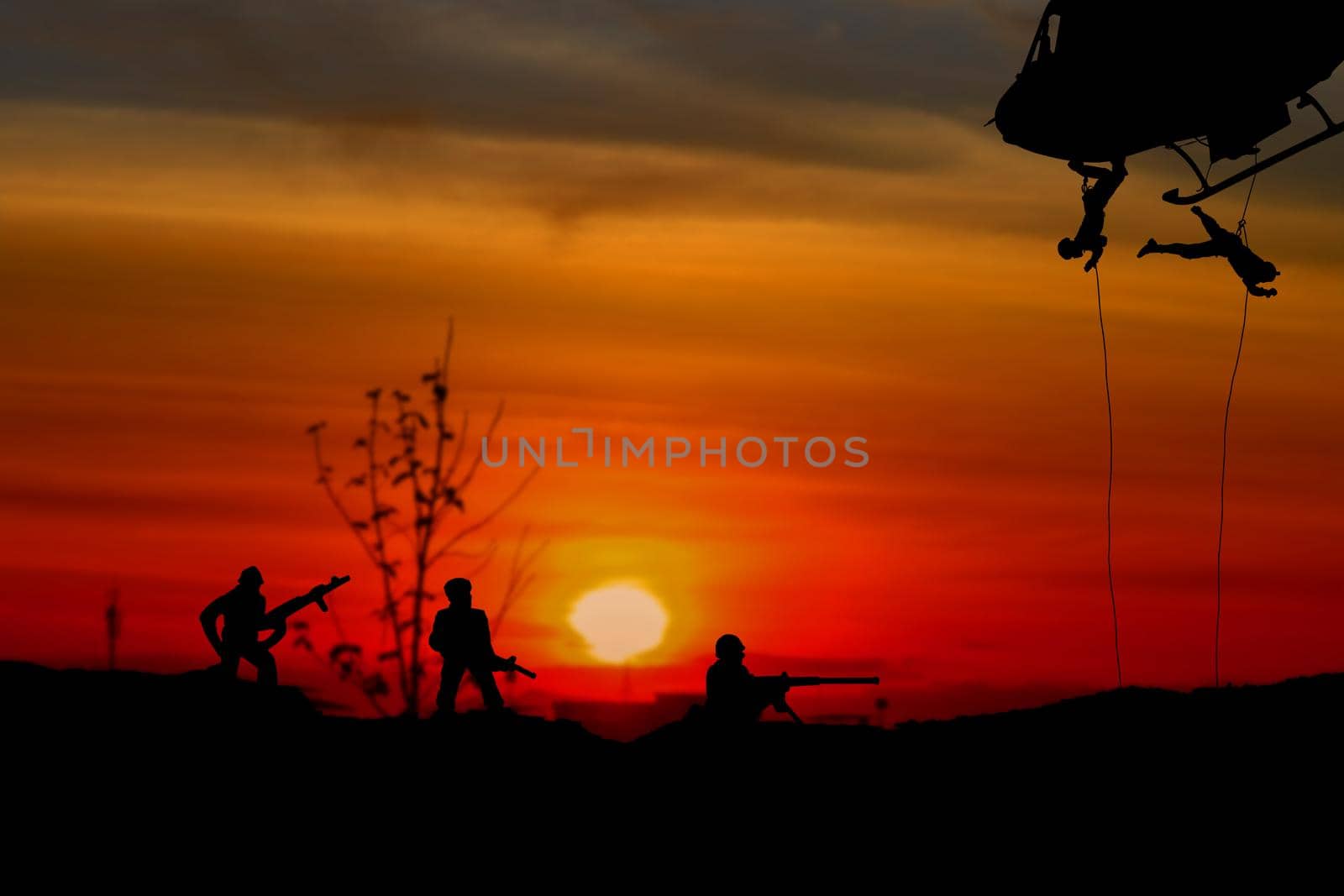Silhouette Soldiers rappel down to attack from helicopter with warrior beware danger On the ground sunset Background blur and copy space add text ( Concept stop hostilities To peace) by pramot