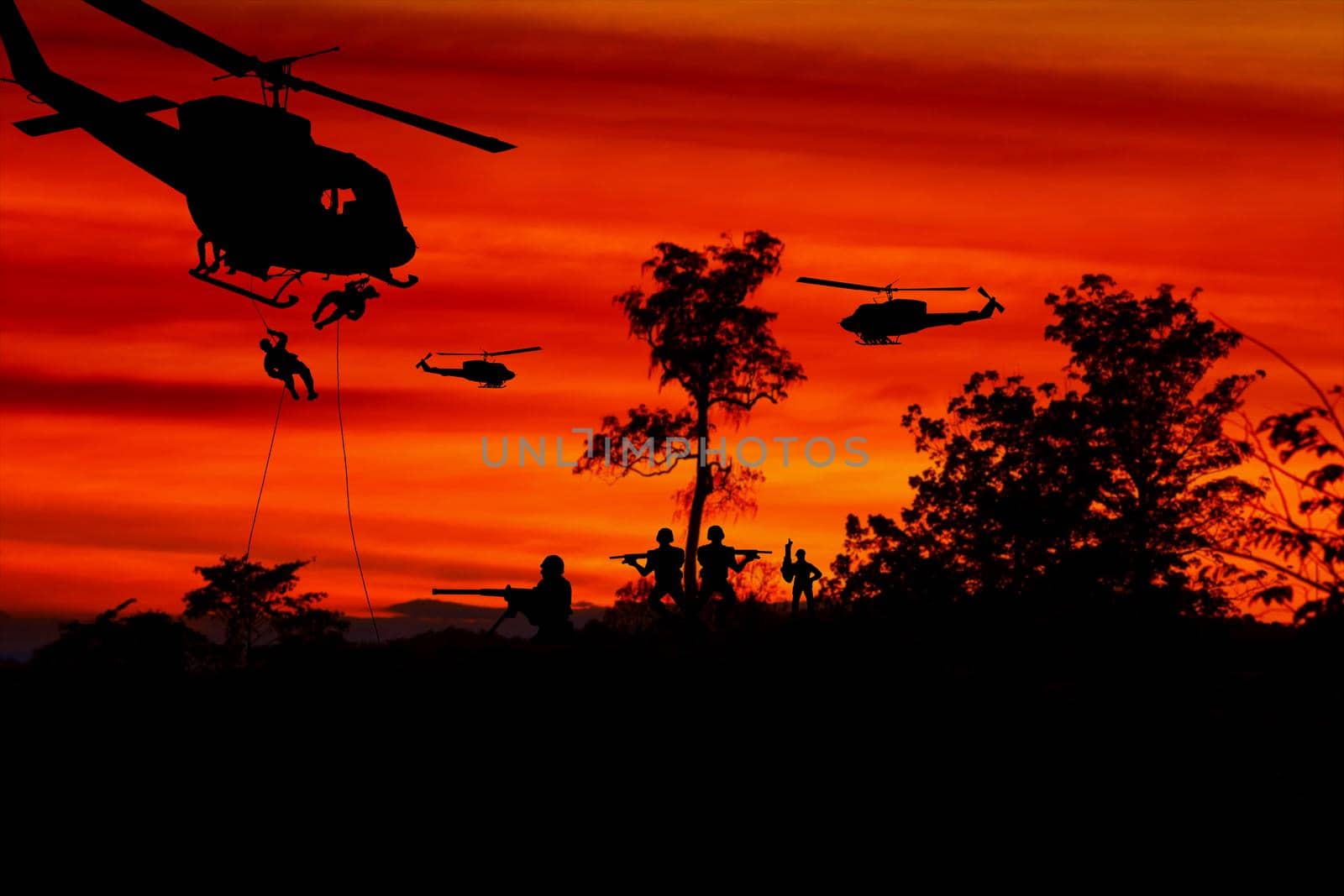 Silhouette Soldiers rappel down to attack from helicopter with warrior beware danger On the ground sunset Background blur and copy space add text ( Concept stop hostilities To peace) by pramot