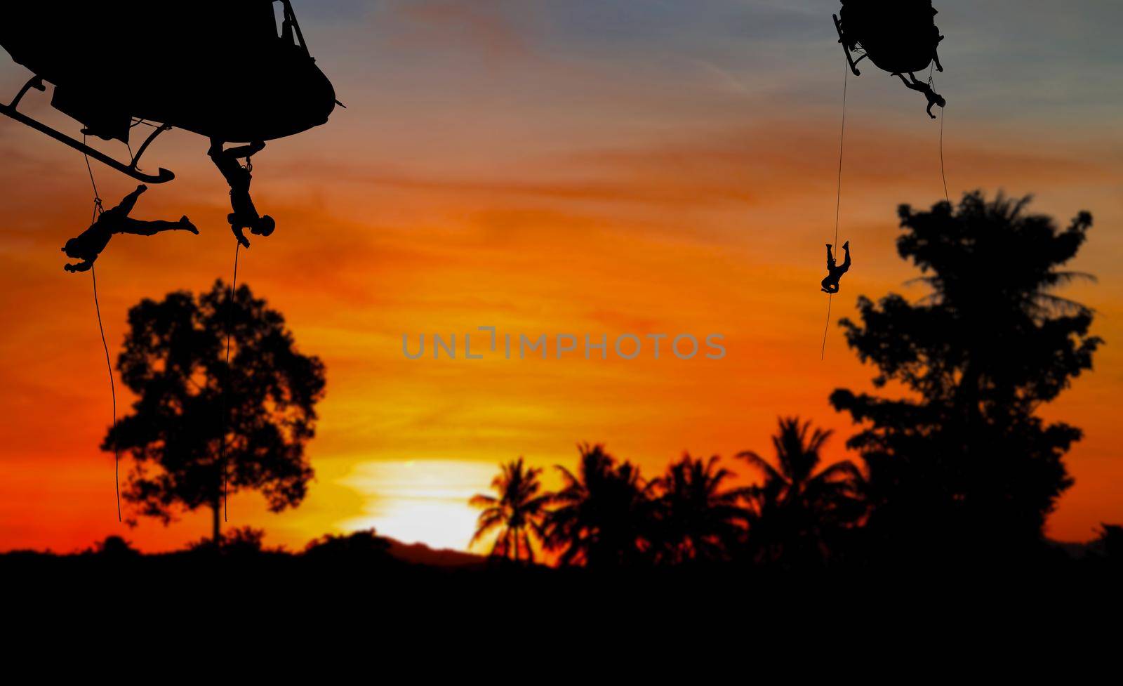 Silhouette Soldiers rappel down to attack from helicopter with sunset and copy space add text ( Concept stop hostilities To peace) by pramot