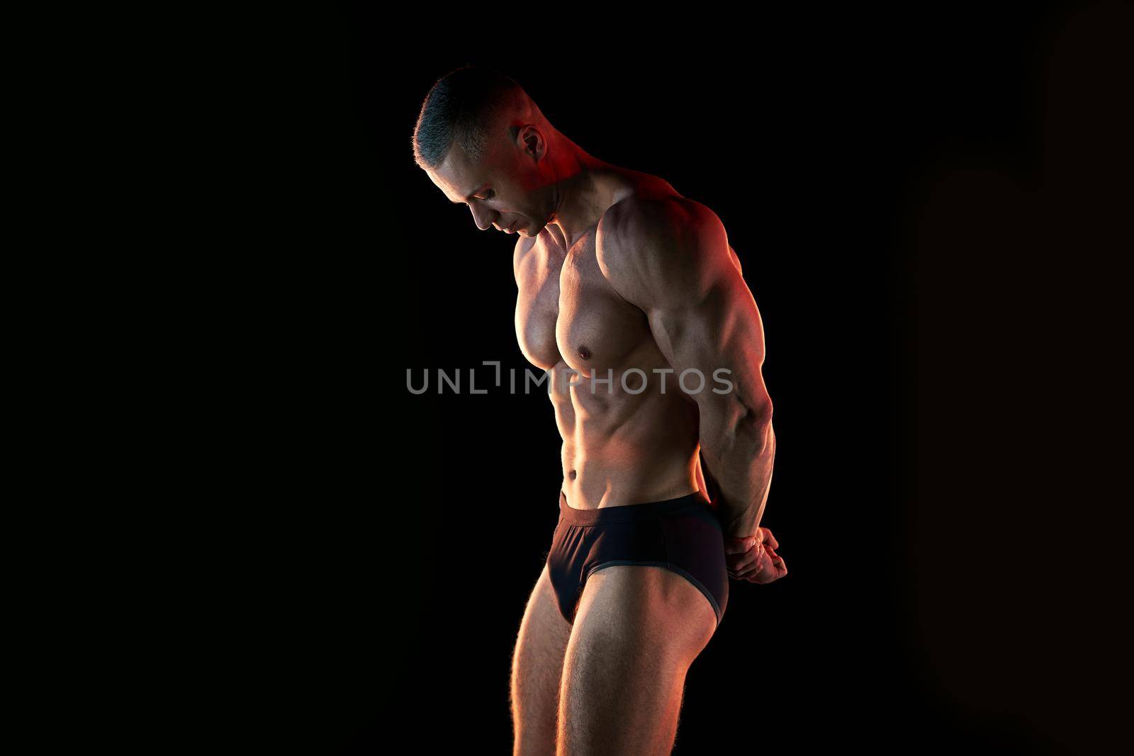 Active lifestyle concept. Professional bodybuilder showing perfect muscular body, lamps illumination on background Sport and fitness concept