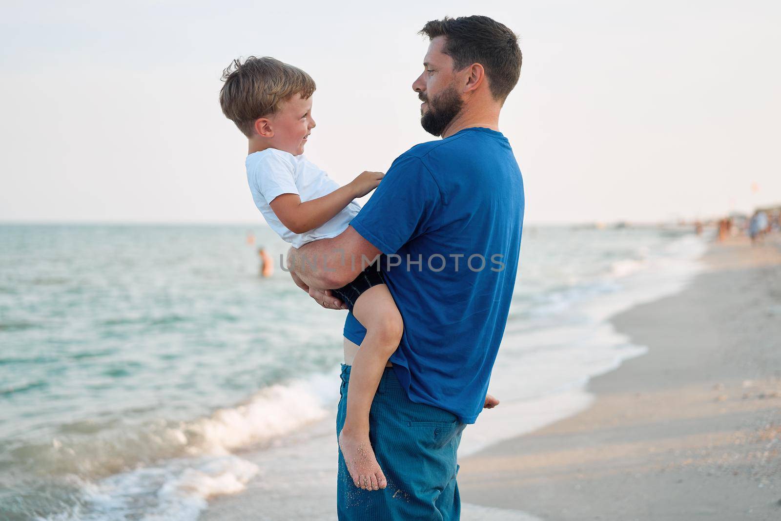 Father son spending time together sea vacation Young dad child little boy walking beach Fathers day. Family with one child. Happy childhood with daddy. sitting on hands laughs