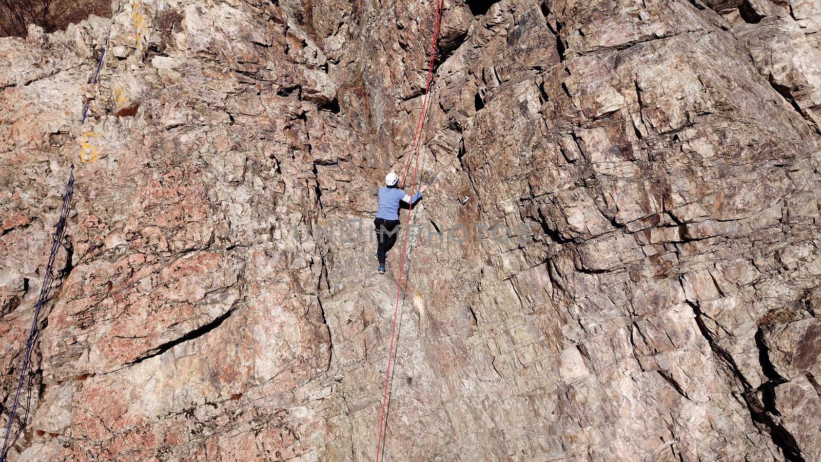 A group of people are engaged in rock climbing. High steep cliff. With the help of a rope, insurance and a partner, climbers climb to the top. Winter time of the year, sometimes there is snow.