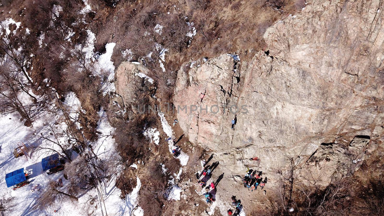 A group of people are engaged in rock climbing. High steep cliff. With the help of a rope, insurance and a partner, climbers climb to the top. Winter time of the year, sometimes there is snow.