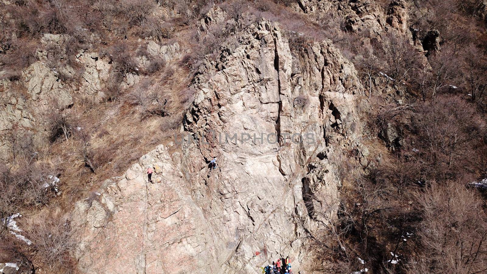 A group of people are engaged in rock climbing. High steep cliff. With the help of a rope, insurance and a partner, climbers climb to the top. Winter time of the year, sometimes there is snow.