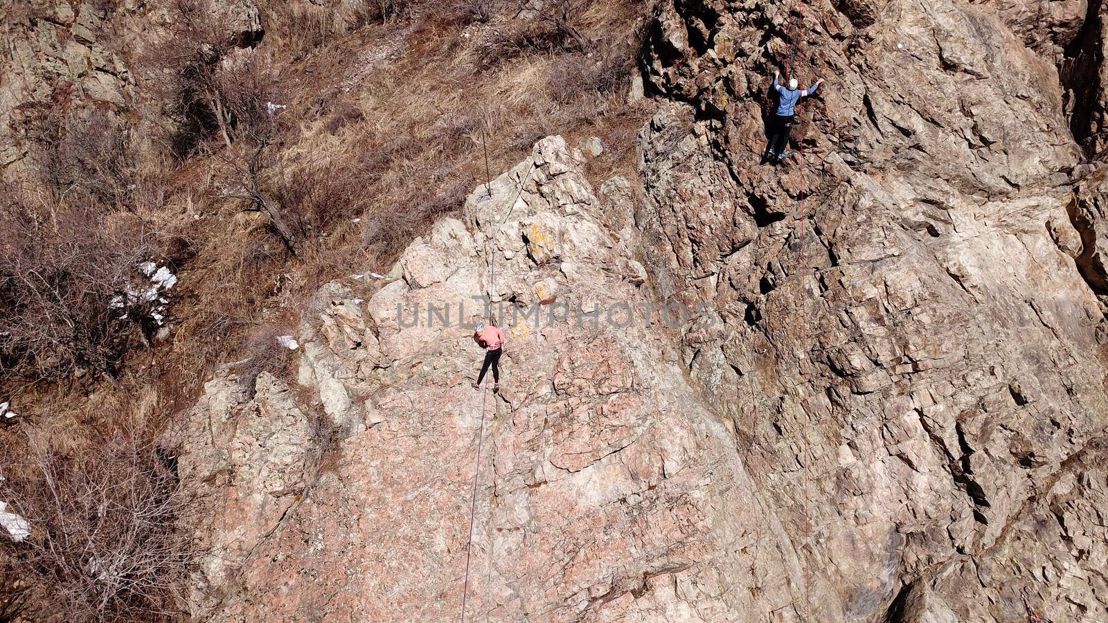 A group of people are engaged in rock climbing. High steep cliff. With the help of a rope, insurance and a partner, climbers climb to the top. Winter time of the year, sometimes there is snow.