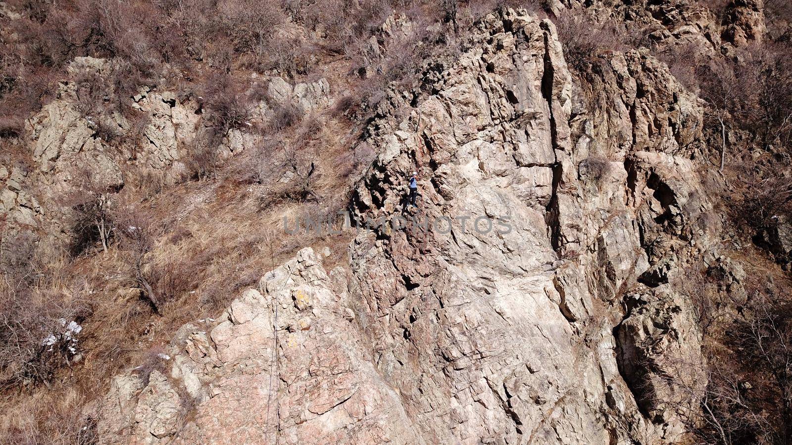 A group of people are engaged in rock climbing. High steep cliff. With the help of a rope, insurance and a partner, climbers climb to the top. Winter time of the year, sometimes there is snow.