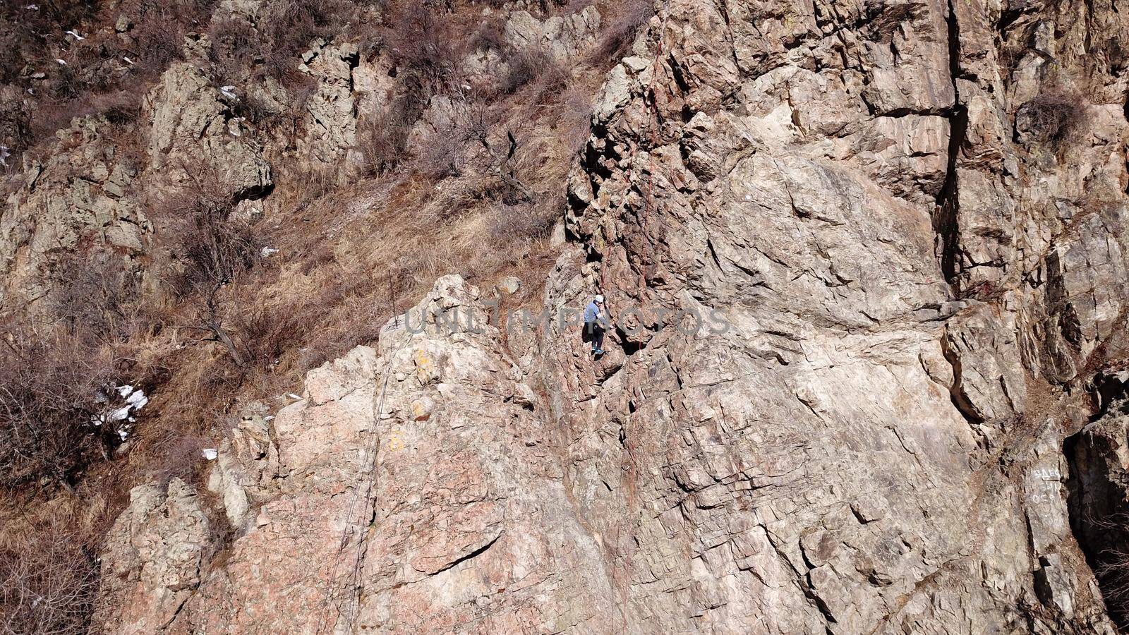 A group of people are engaged in rock climbing. High steep cliff. With the help of a rope, insurance and a partner, climbers climb to the top. Winter time of the year, sometimes there is snow.