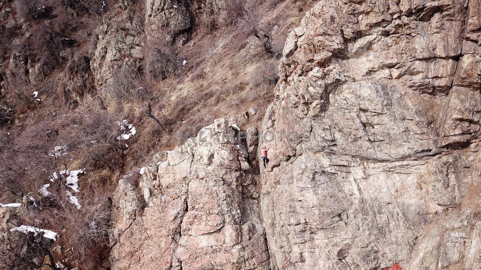 A group of people are engaged in rock climbing. High steep cliff. With the help of a rope, insurance and a partner, climbers climb to the top. Winter time of the year, sometimes there is snow.