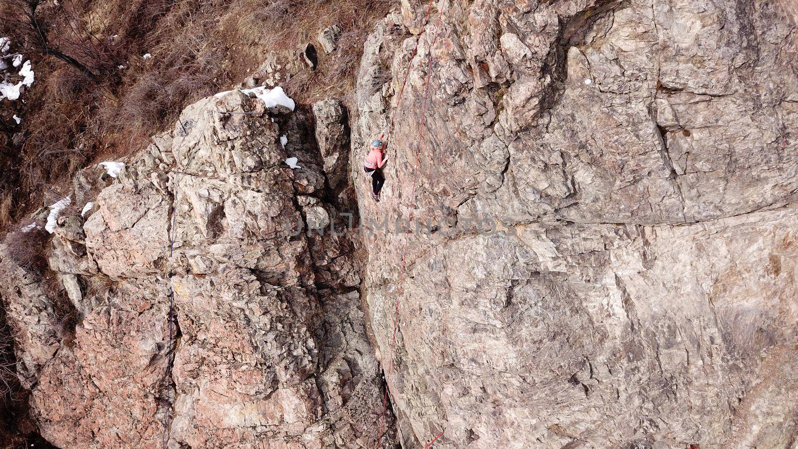 A group of people are engaged in rock climbing. High steep cliff. With the help of a rope, insurance and a partner, climbers climb to the top. Winter time of the year, sometimes there is snow.