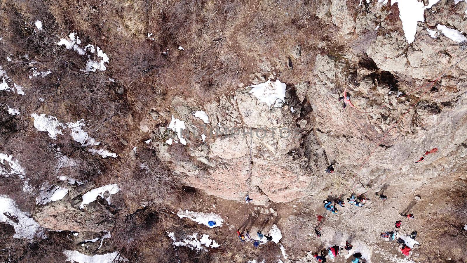 A group of people are engaged in rock climbing. High steep cliff. With the help of a rope, insurance and a partner, climbers climb to the top. Winter time of the year, sometimes there is snow.