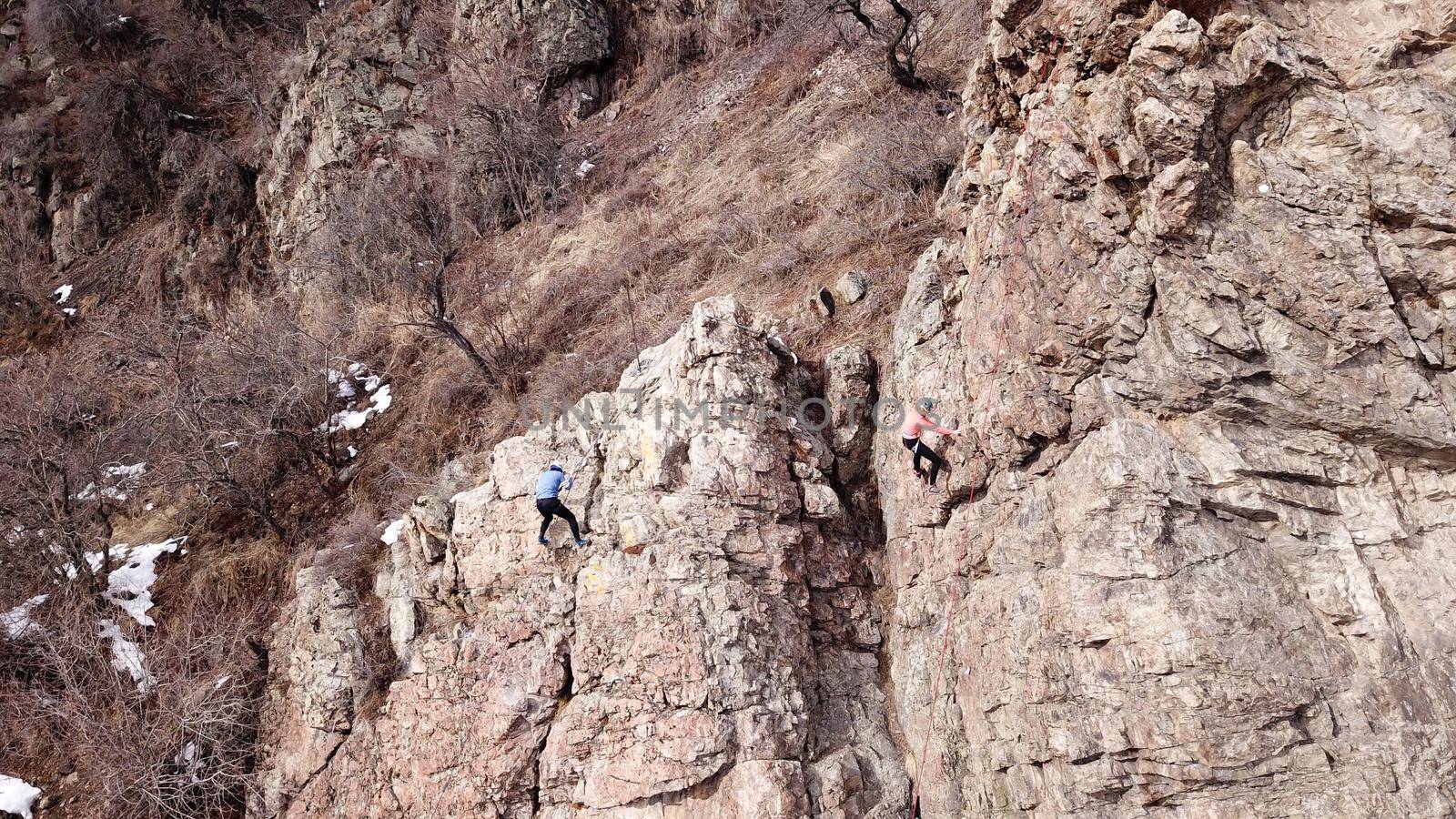 A group of people are engaged in rock climbing. High steep cliff. With the help of a rope, insurance and a partner, climbers climb to the top. Winter time of the year, sometimes there is snow.