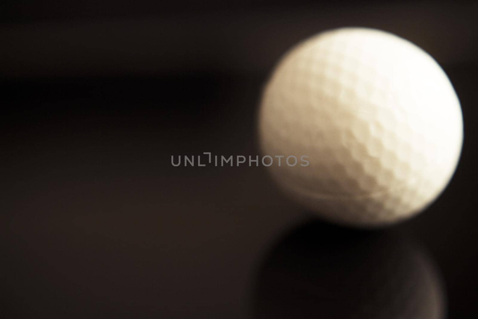 White golf ball somewhat out of focus on dark background. No people