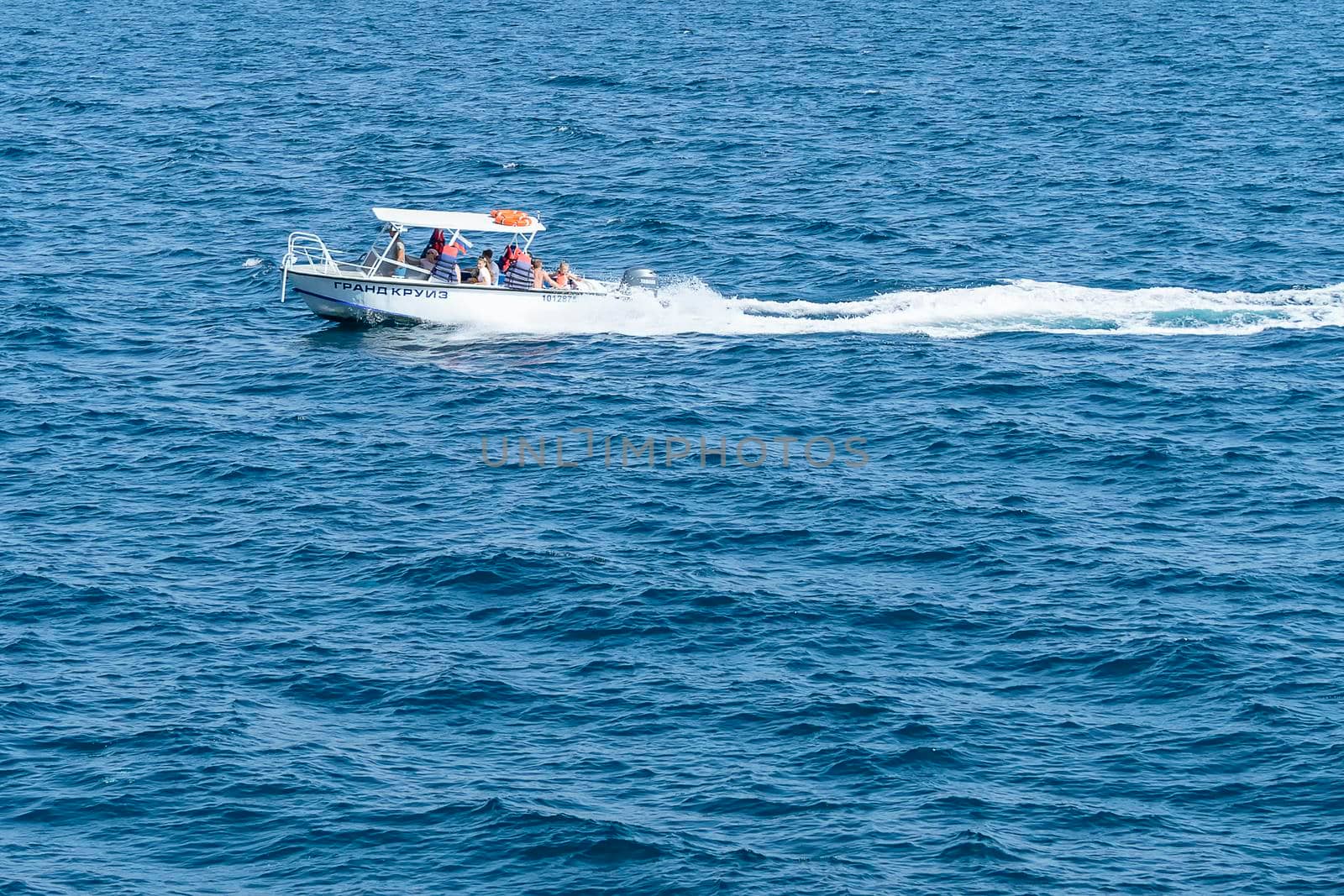 White fast boat sails by sea. Sunny autumn day. Side view. Crimea, Sudak - 10 October 2020. by Essffes