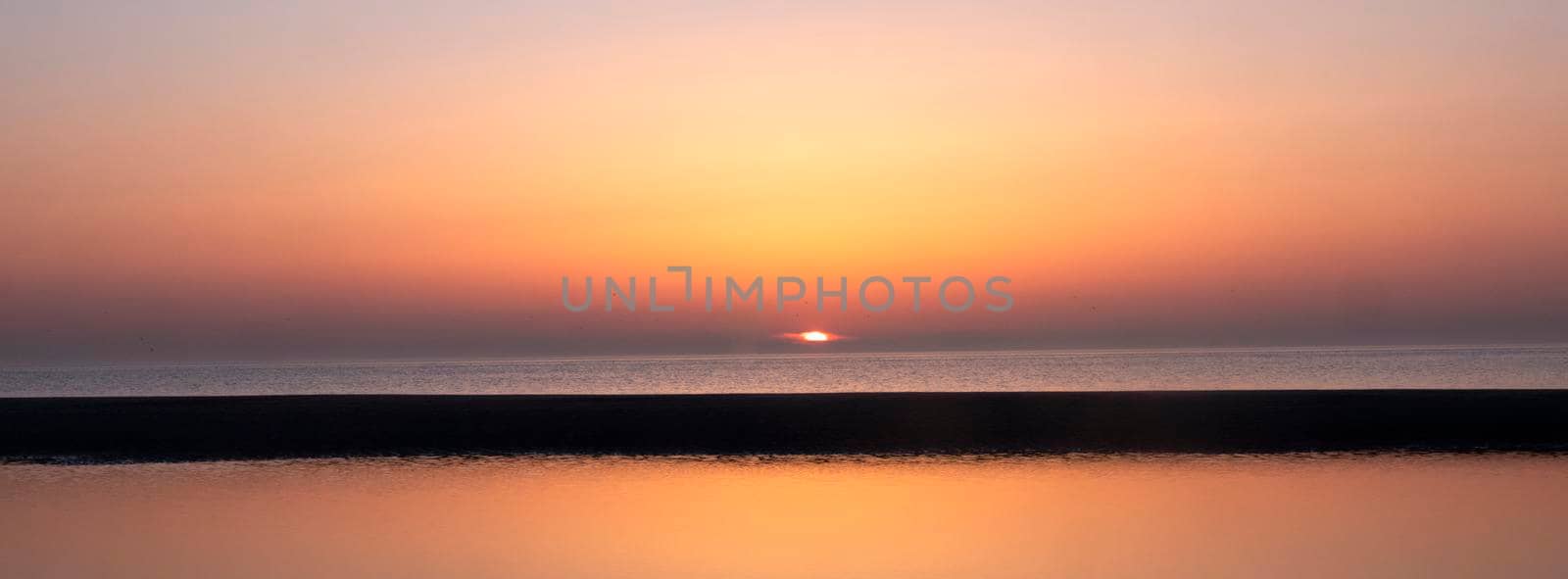 reflection of colorful sunset in water near beach by ahavelaar