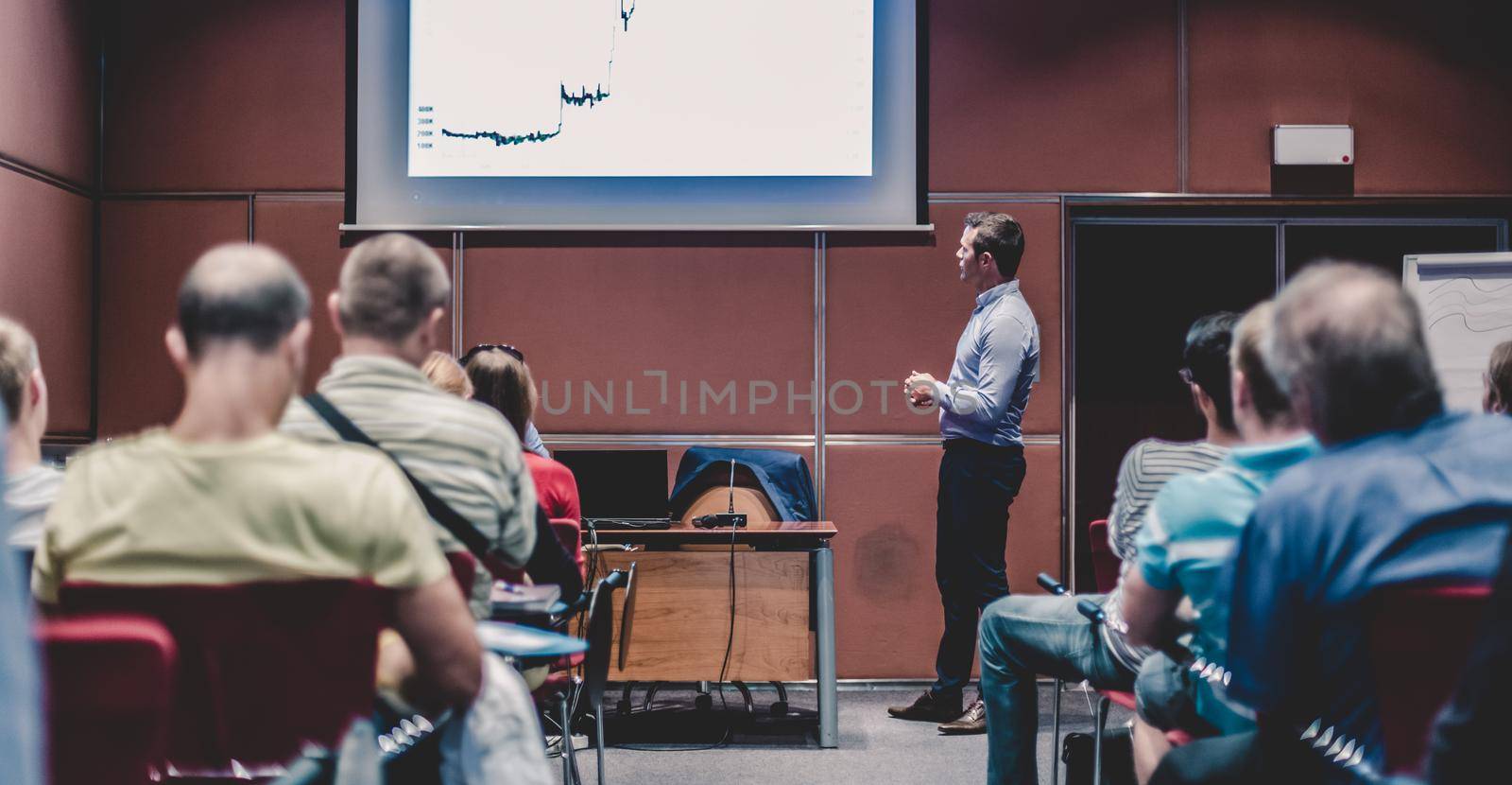 Speaker giving a talk in conference hall at business event. Unrecognizable people in audience at conference hall. Business and Entrepreneurship concept.