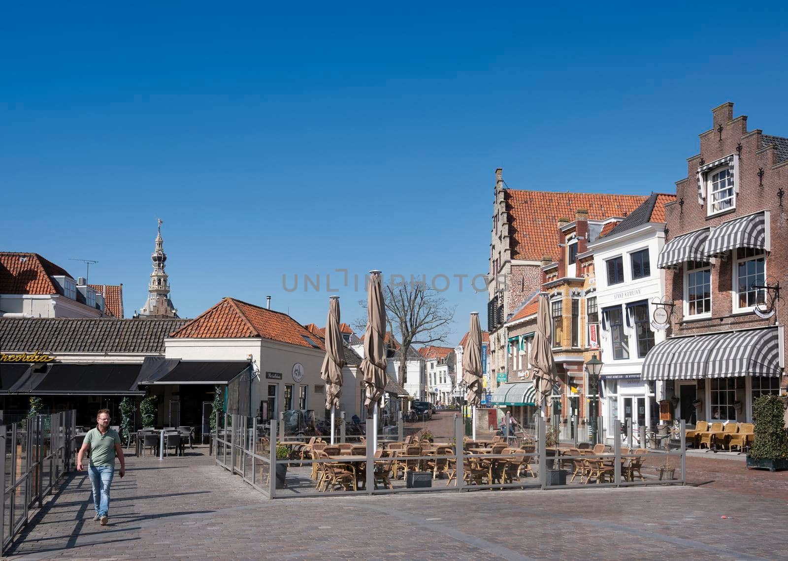 zierikzee, netherlands, 30 march 2021: man on square in centre old city zierikzee under blue sky in spring