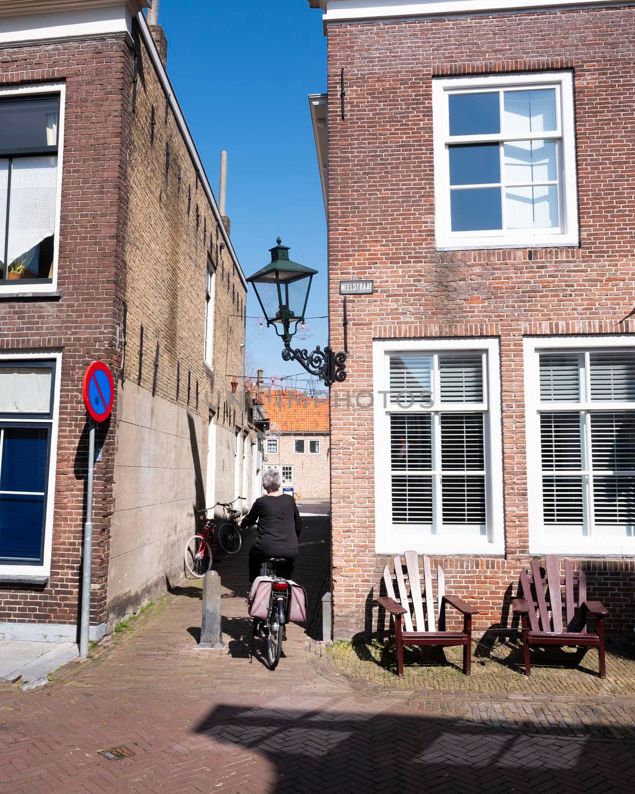 zierikzee, netherlands, 30 march 2021: woman on bicycle in old town of zierikzee in dutch province of zeeland under blue sky