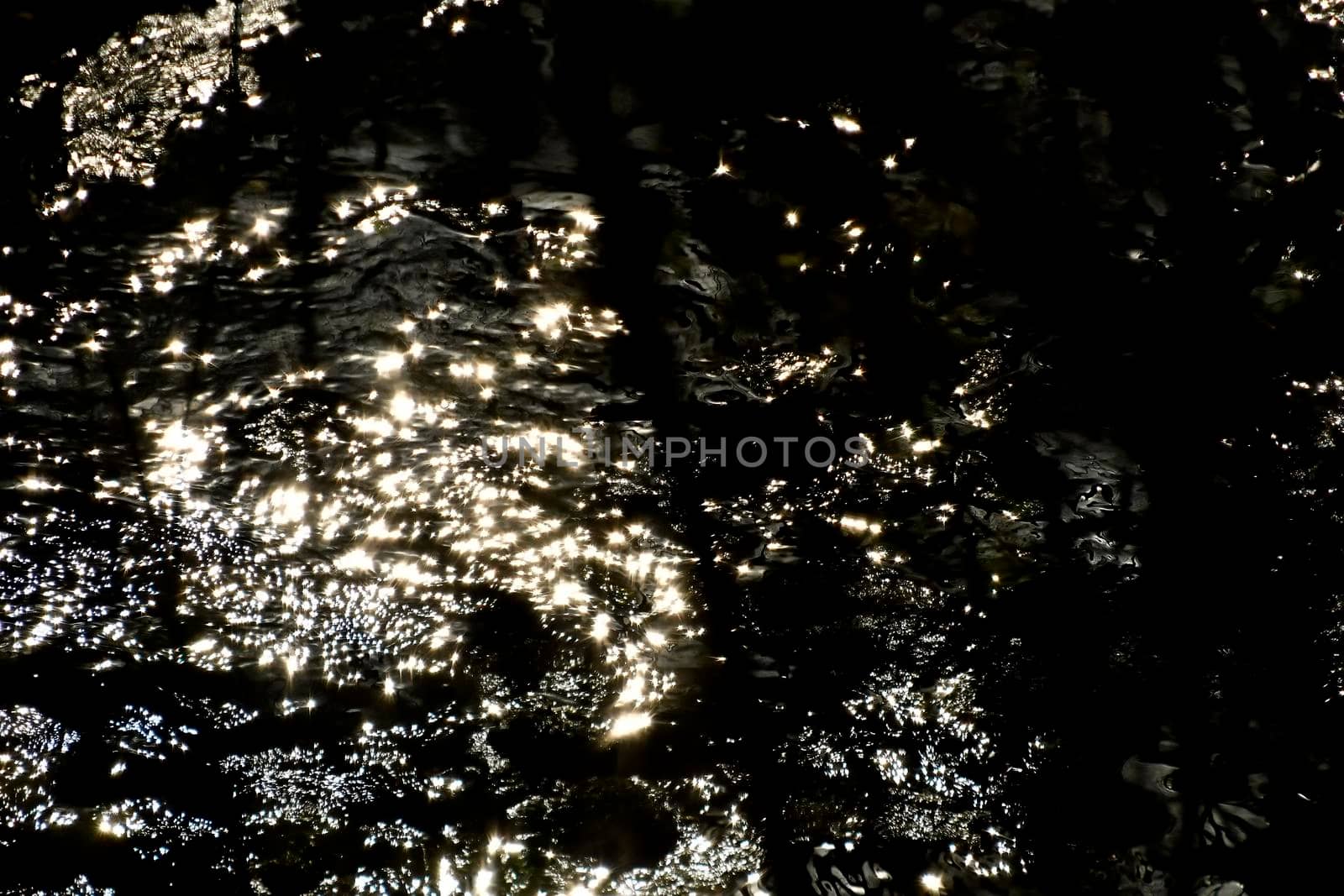 Water of a creek with sun reflections by Jochen