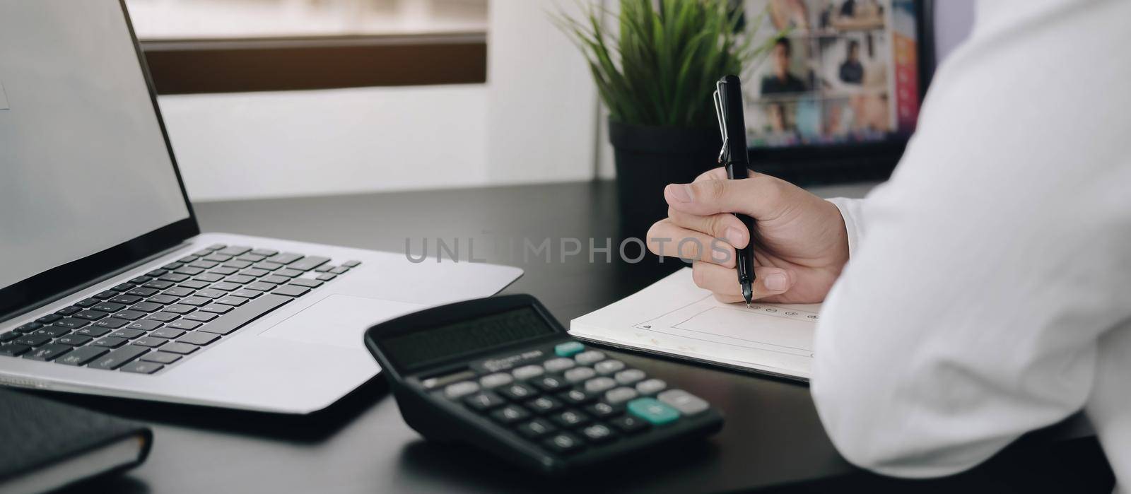Cropped shot of woman freelancer writing on notebook on table in office by wichayada