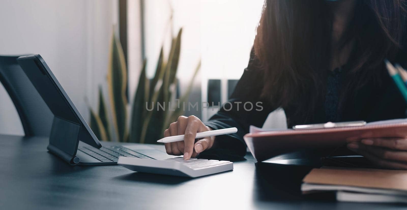 Close up Business woman using calculator and laptop for do math finance on wooden desk in office and business working background, tax, accounting, statistics and analytic research concept.