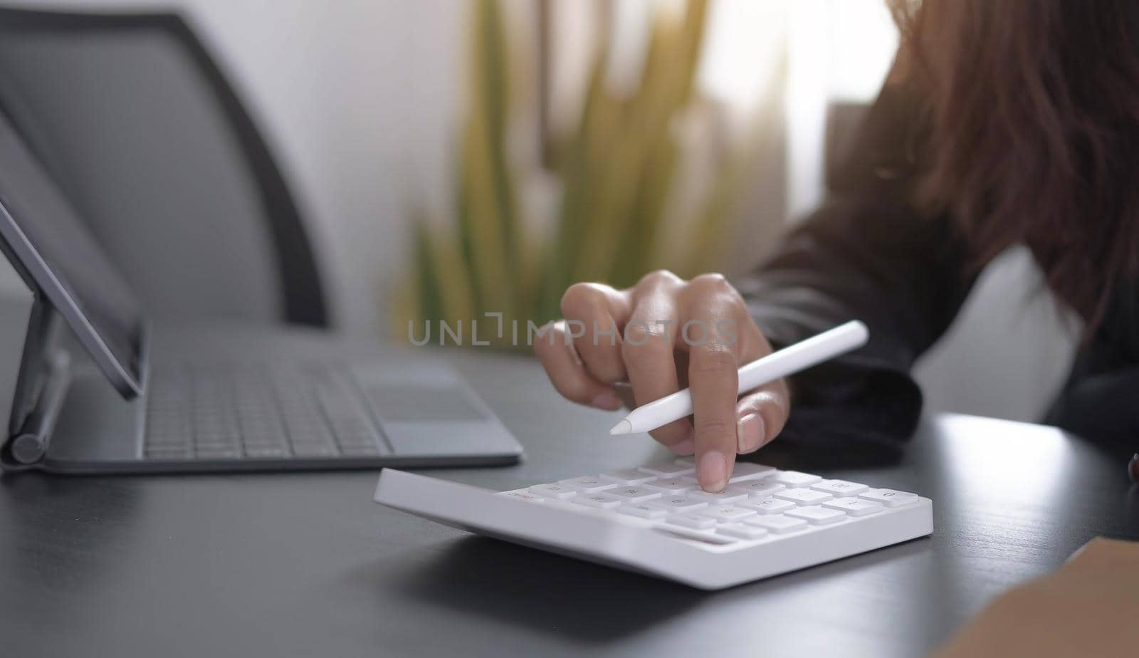 Close up Business woman using calculator and laptop for do math finance on wooden desk in office and business working background, tax, accounting, statistics and analytic research concept.