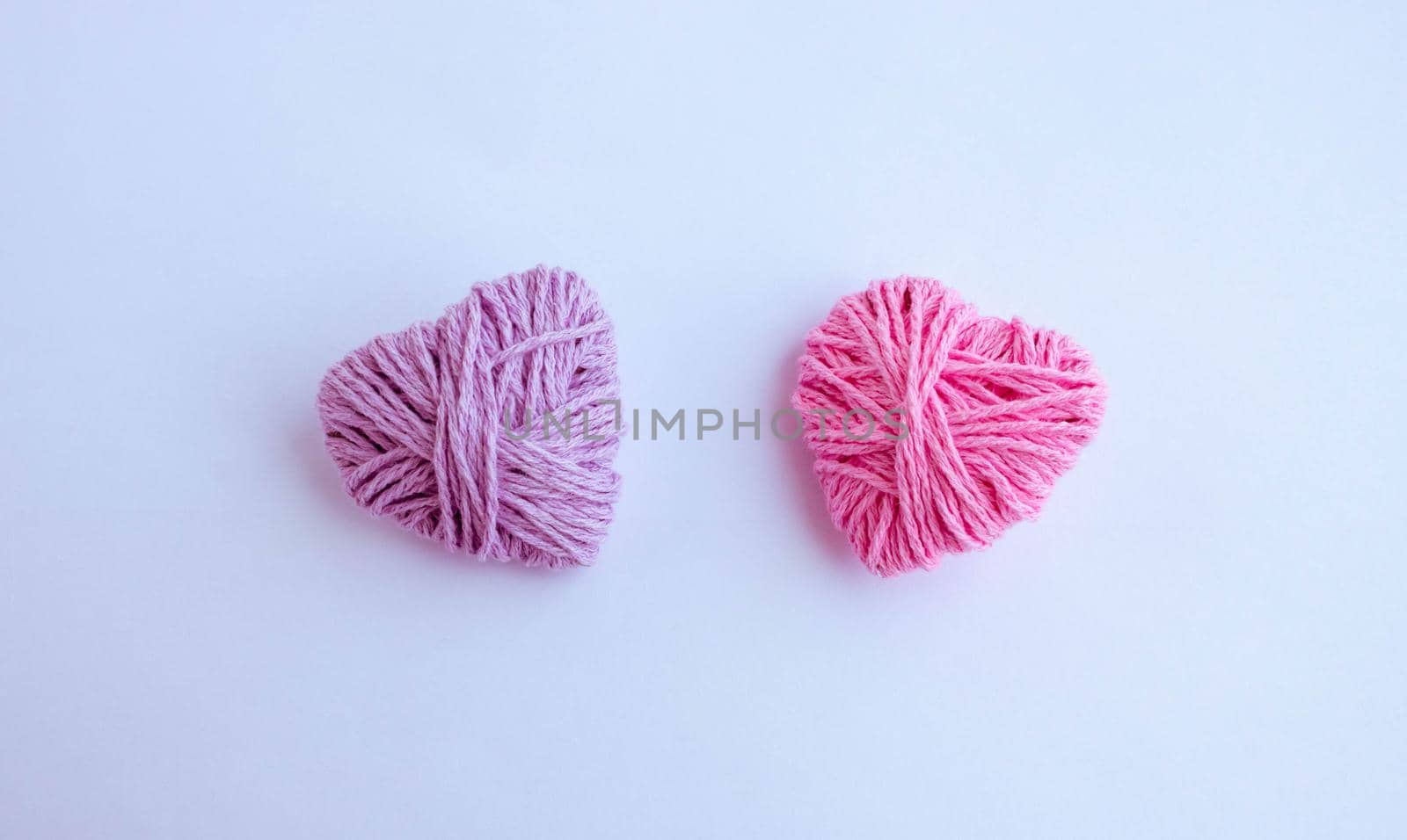 Two thread hearts hang on a white background. Holiday card, background. The concept of Valentine's Day, March 8, Mother's Day.