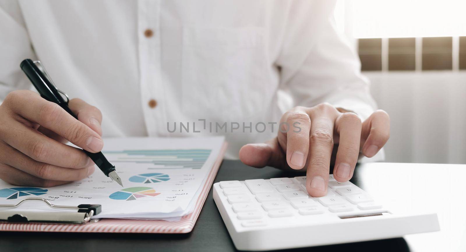 Close up Businessman using calculator and laptop for do math finance on wooden desk in office and business working background, tax, accounting, statistics and analytic research concept.