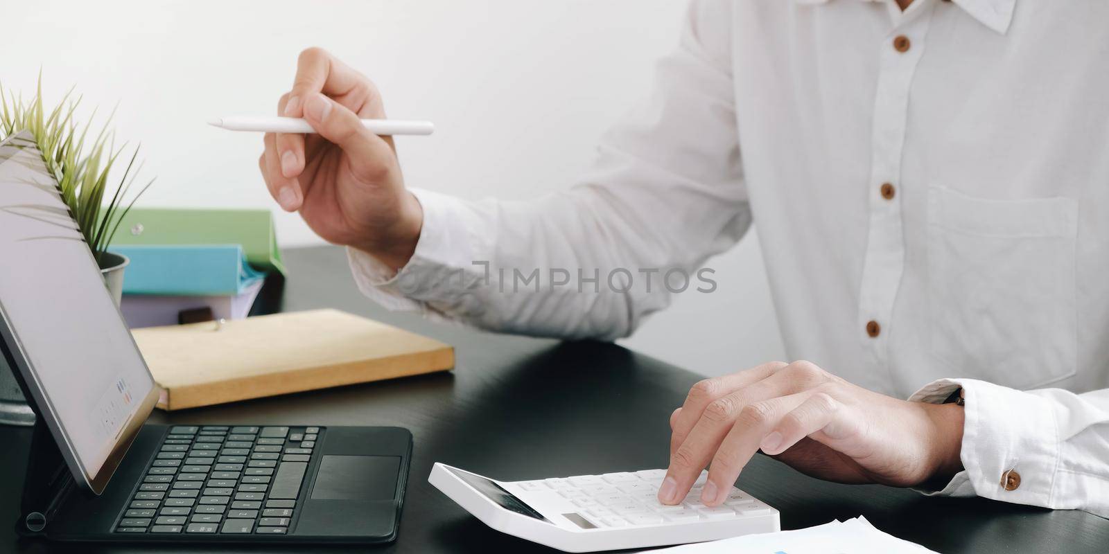Close up Businessman using calculator and laptop for do math finance on wooden desk in office and business working background, tax, accounting, statistics and analytic research concept.