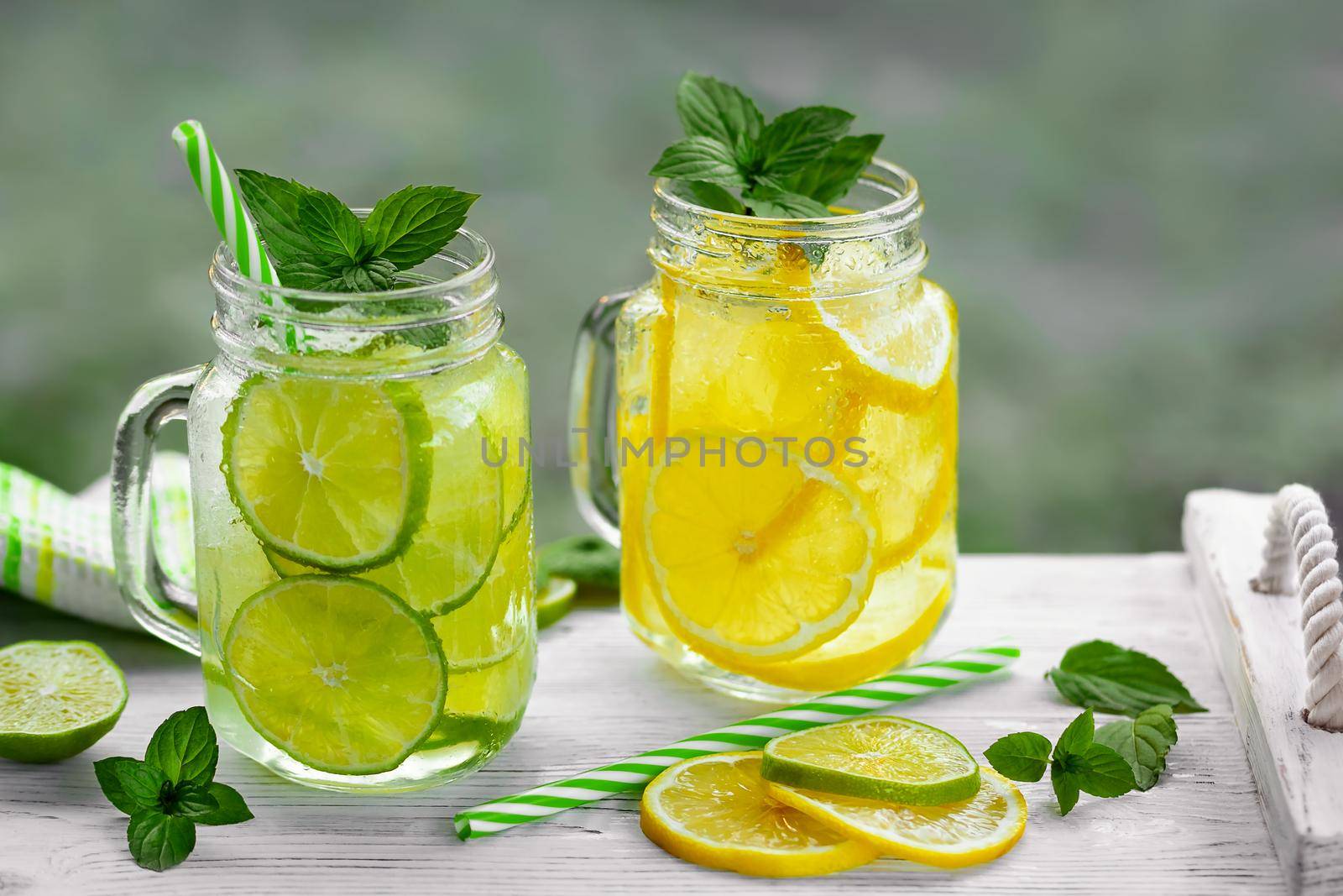 Cold refreshing homemade lemonade with mint, lemon and lime in mason jars.